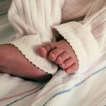 Adorable close-up photo of newborn baby feet clad in soft striped pajamas, symbolizing innocence and warmth.