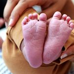 Tender close-up of a baby's feet cradled in a parent's hands, expressing love and care.